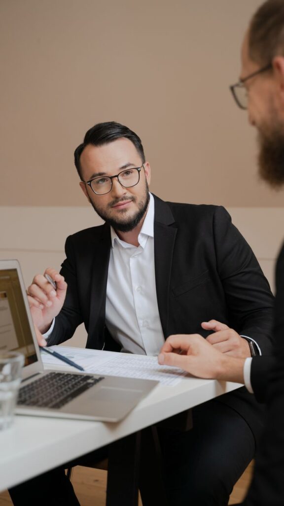 The Entrepreneur’s Guide to Turning Ideas Into Profitable Two businessmen in a meeting discussing strategies with laptops and documents.